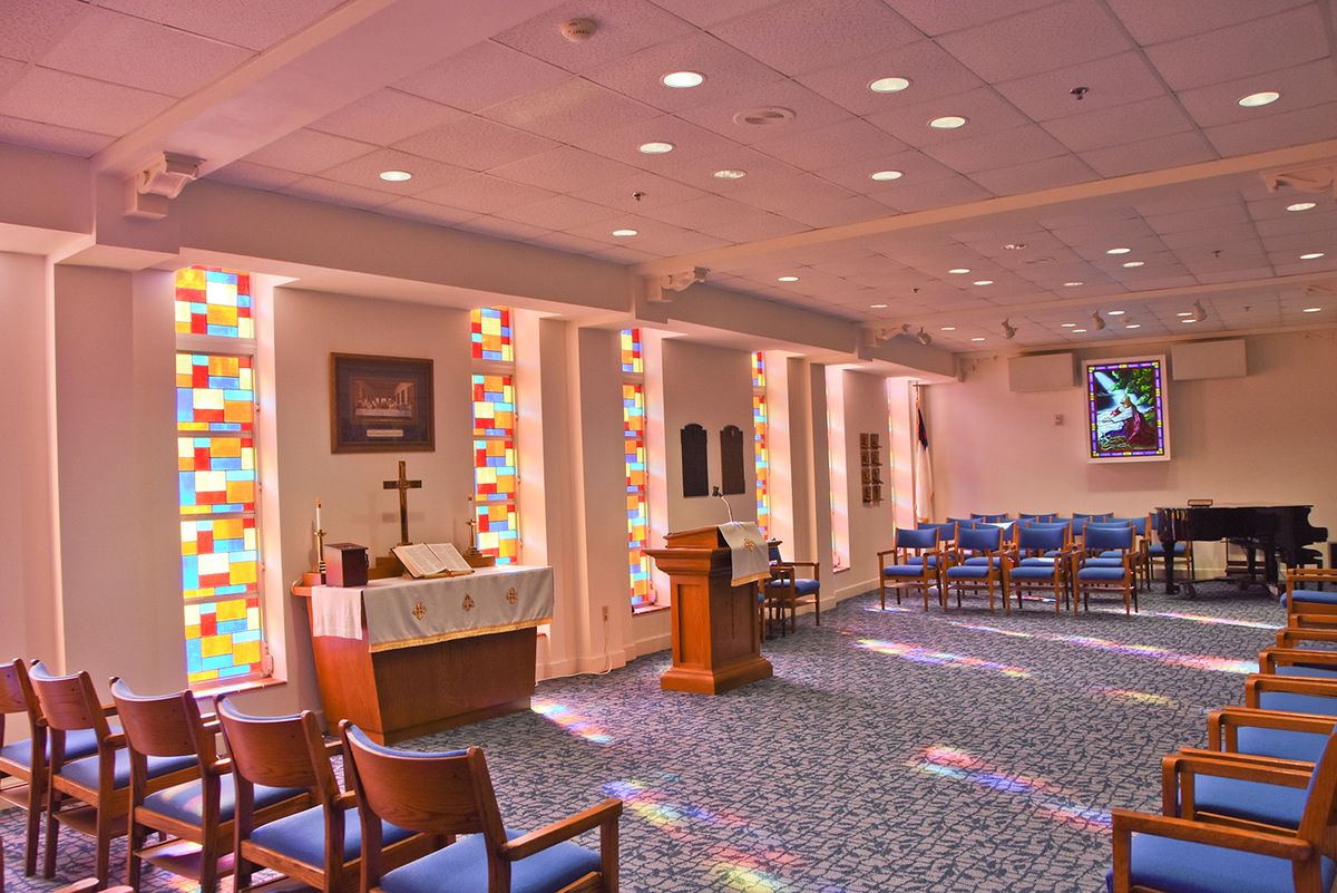 A serene chapel interior featuring stained glass windows and an altar.