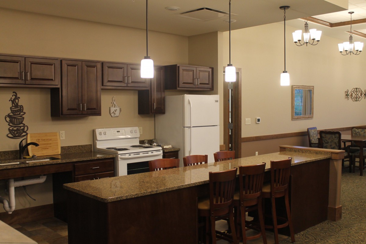 A modern kitchen with dark wood cabinets, a large island countertop, and appliances.