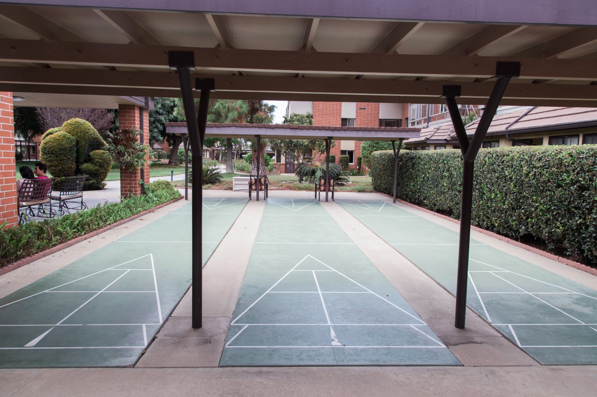 An outdoor covered shuffleboard court with two lanes marked by lines.