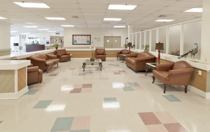 A spacious waiting room with brown leather chairs and tiled flooring.
