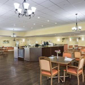 A spacious dining area with tables and chairs arranged neatly under elegant chandeliers.