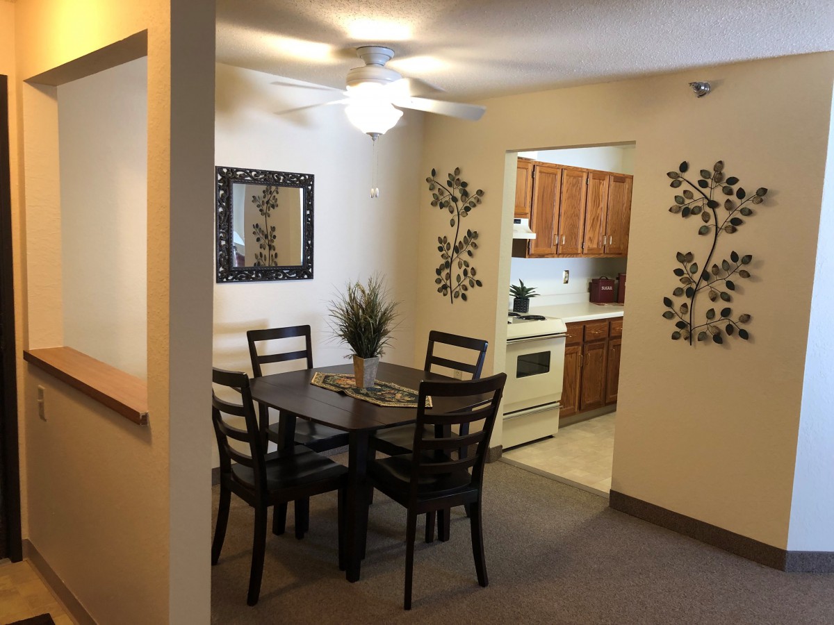 A cozy dining area featuring a wooden table and chairs, with access to a compact kitchen.