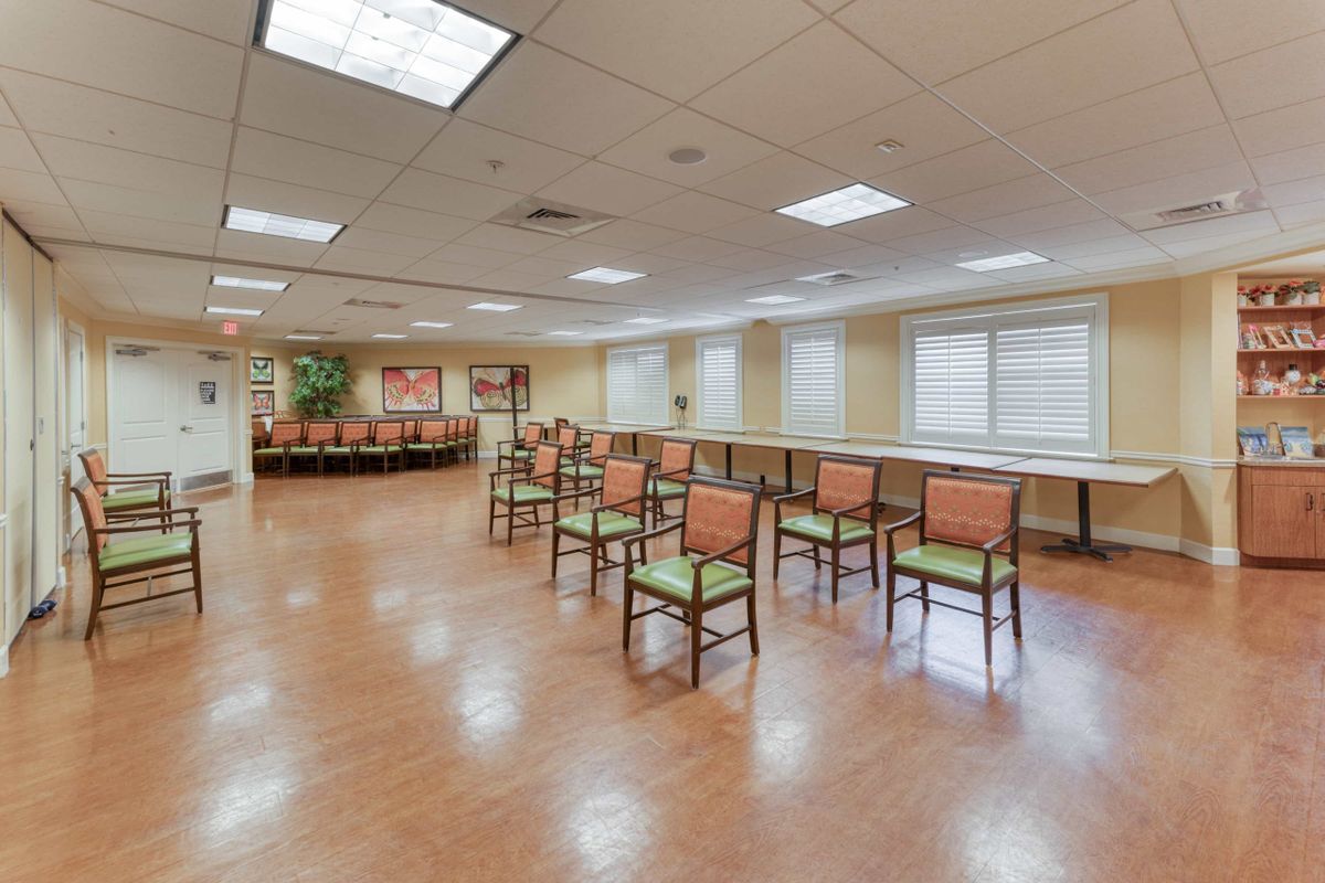 An empty meeting room with arranged chairs and wooden flooring.