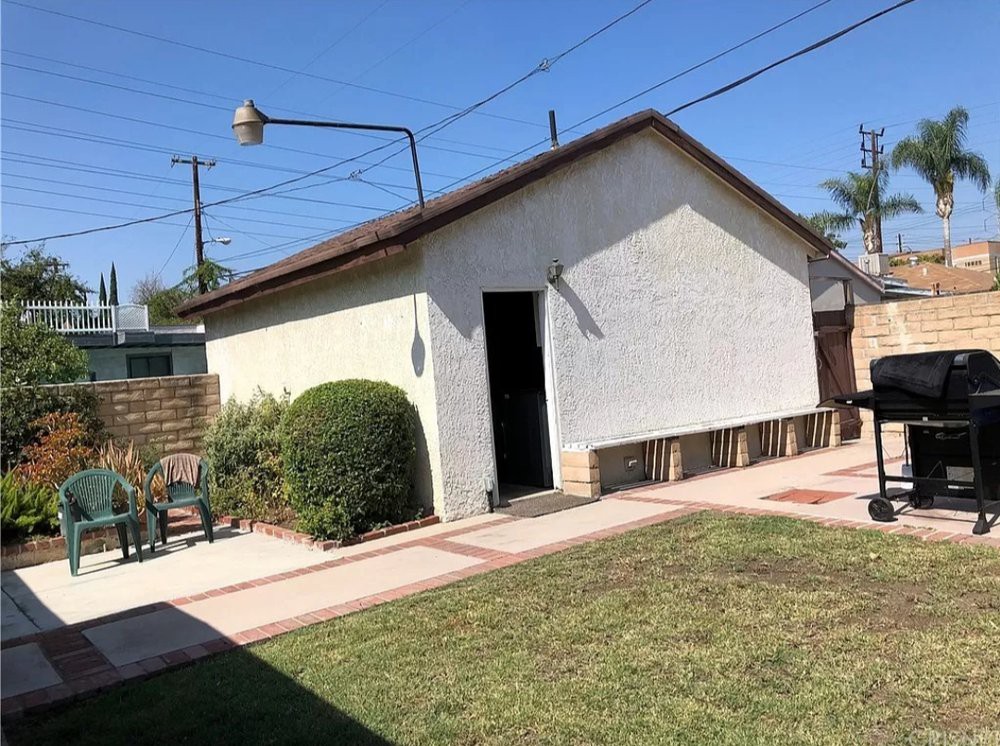 A sunny backyard featuring a small shed and well-kept lawn.