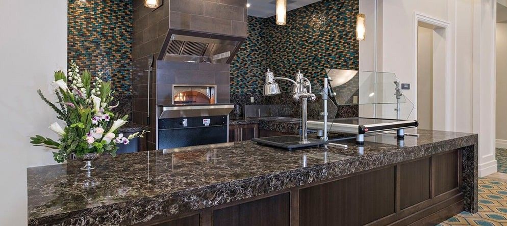 A modern kitchen featuring a marble countertop and a built-in pizza oven.
