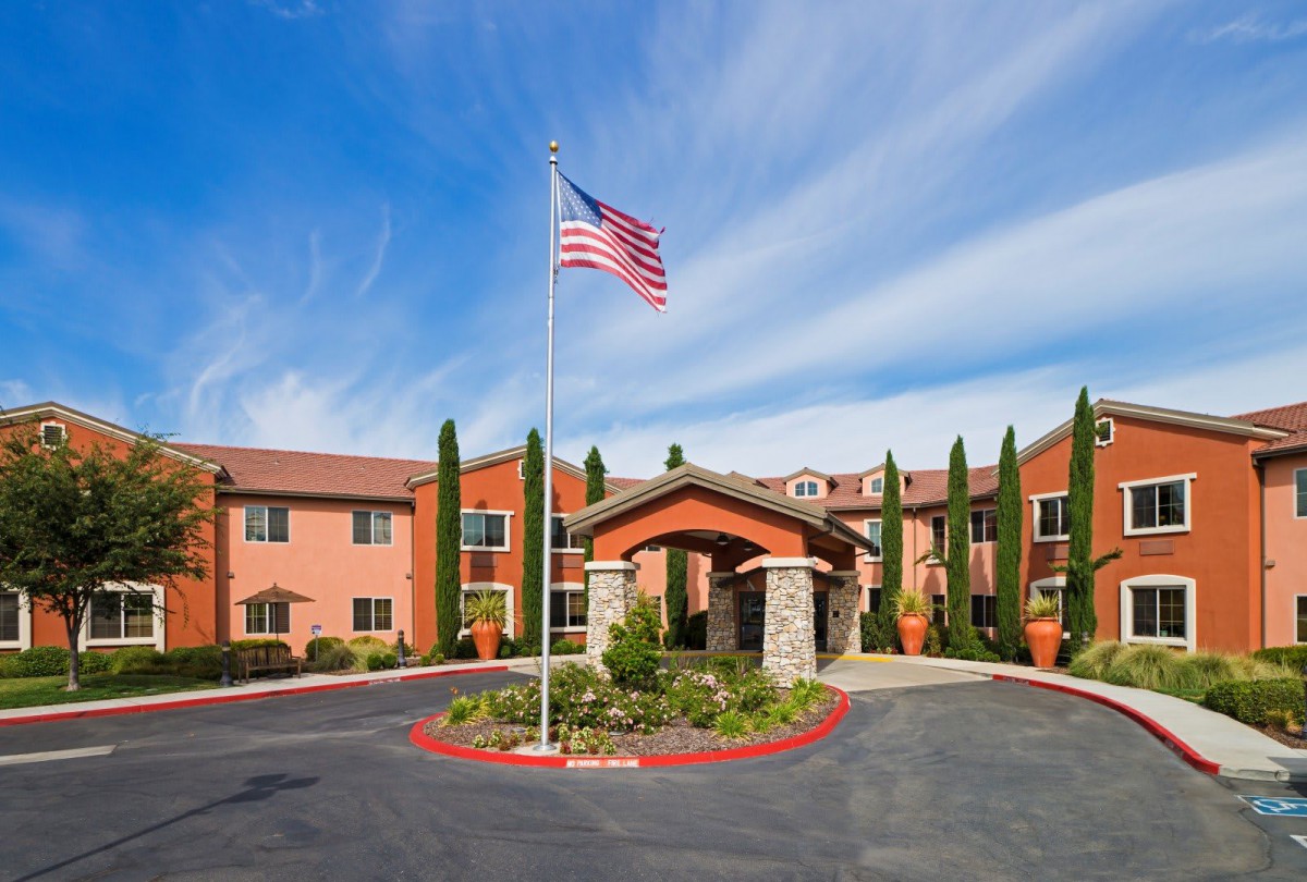 A hotel entrance with a flagpole displaying the American flag and well-maintained landscaping.