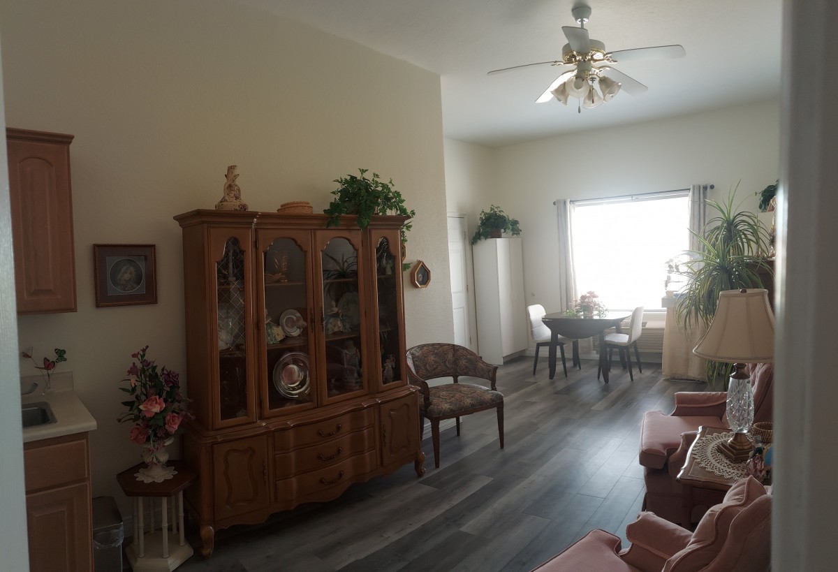 A cozy living and dining area featuring a china cabinet, chairs, and a ceiling fan with ample natural light.