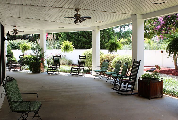 A peaceful covered porch with rocking chairs and lush greenery.