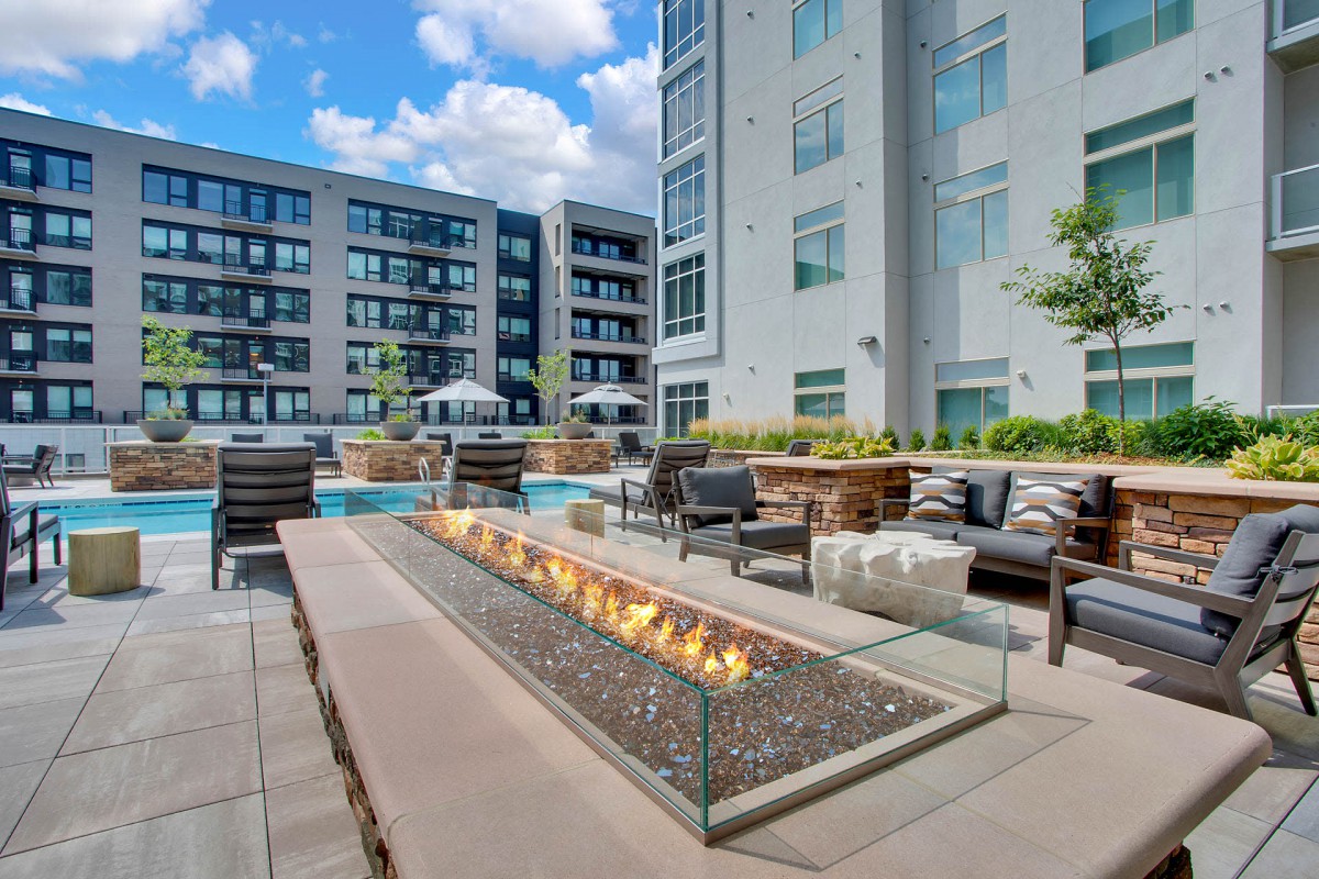 A modern apartment complex features a stylish outdoor seating area with a fire pit.