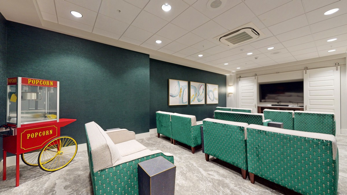 A modern lounge area with green upholstered chairs and framed artwork on the wall.