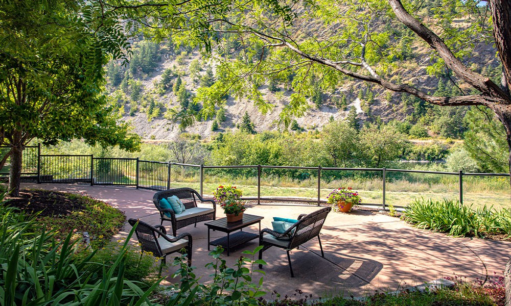A tranquil patio setting with comfortable seating overlooking a lush, green landscape.