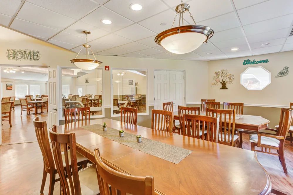 A spacious dining room with wooden tables and chairs, illuminated by elegant chandeliers.