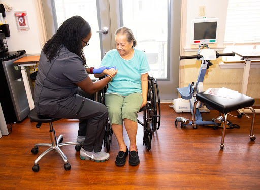 A healthcare worker taking the blood pressure of an elderly patient in a comfortable setting.