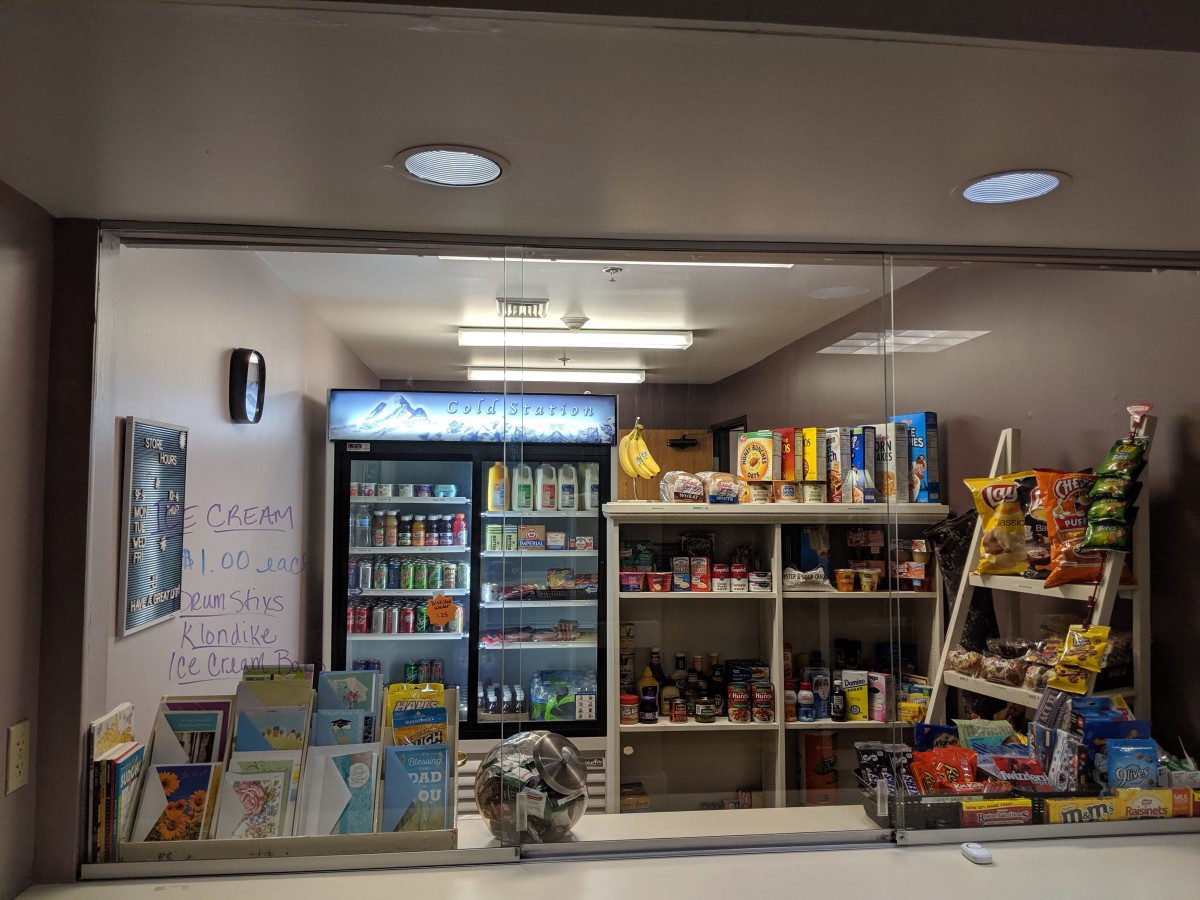 Interior view of a small store with shelves stocked with various products including beverages and snacks.
