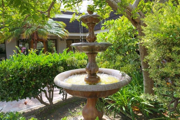A decorative garden fountain surrounded by lush greenery.