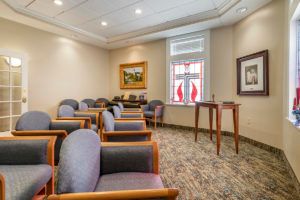 A well-lit waiting room with several chairs, paintings on the walls, and a window letting in natural light.