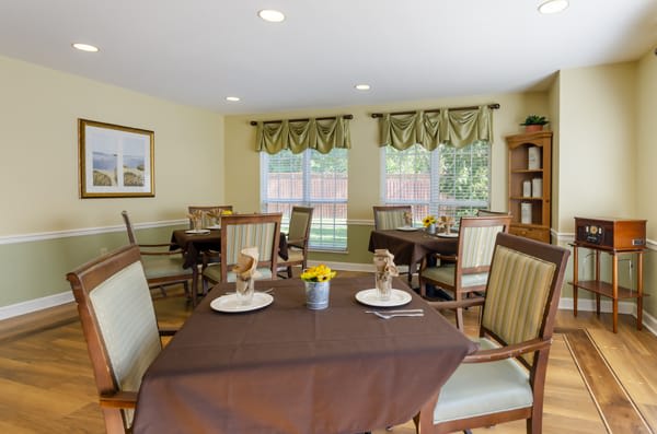 A cozy dining room with neatly arranged tables and chairs, featuring elegant window decor.