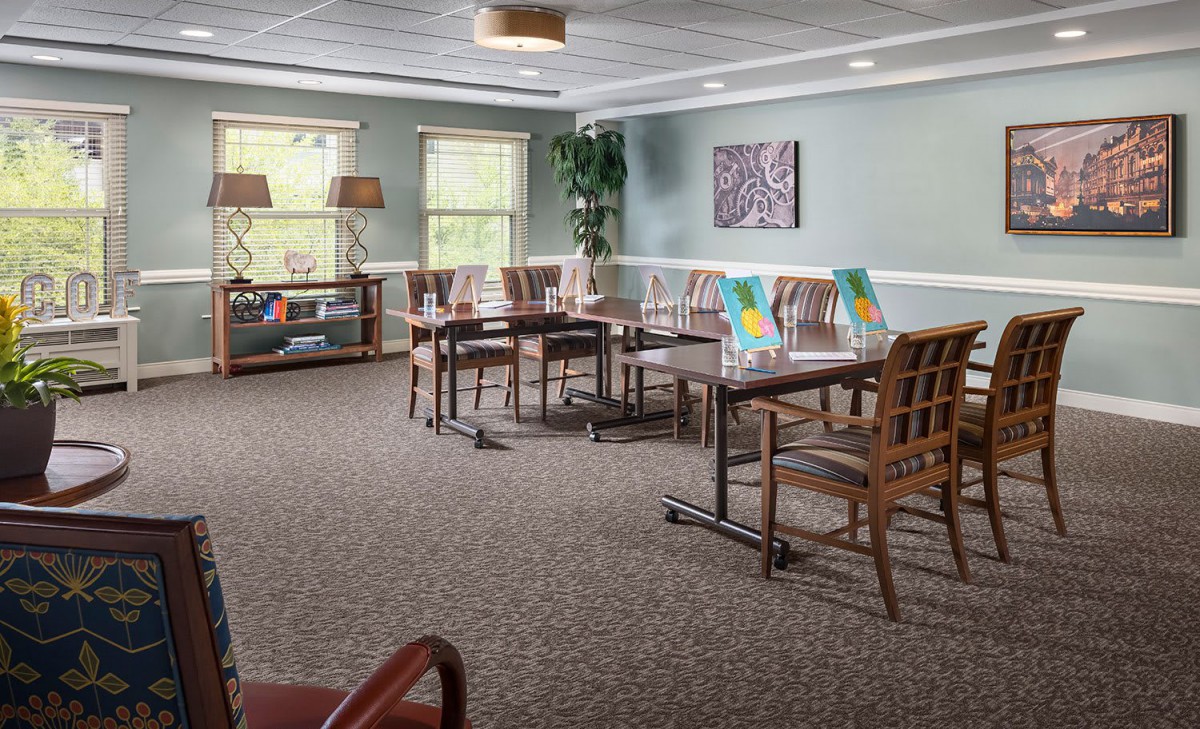 A spacious dining area with neatly arranged tables and chairs, decorated with artwork and plants for a cozy atmosphere.