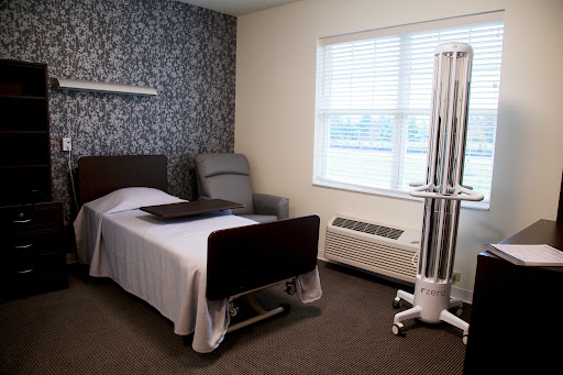 A neatly arranged patient room in a healthcare facility, featuring a hospital bed and comfortable seating.