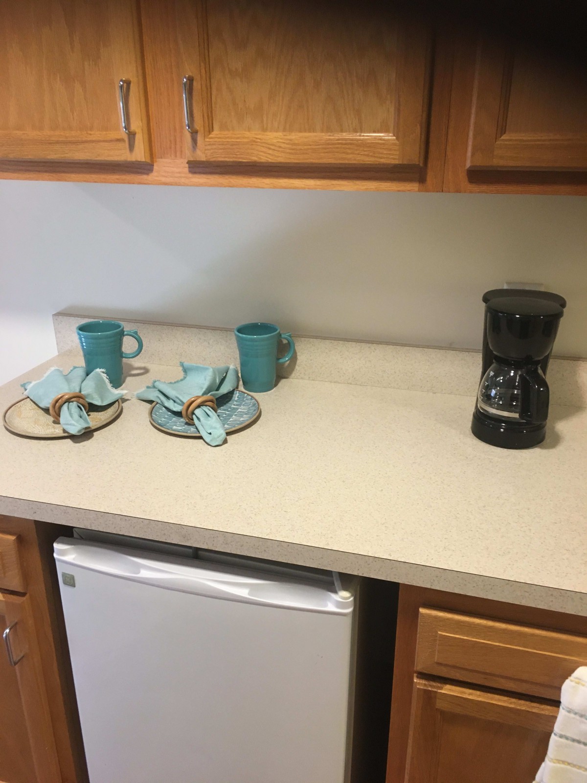 A kitchen countertop with two mugs, a stack of dish towels, and a coffee maker.