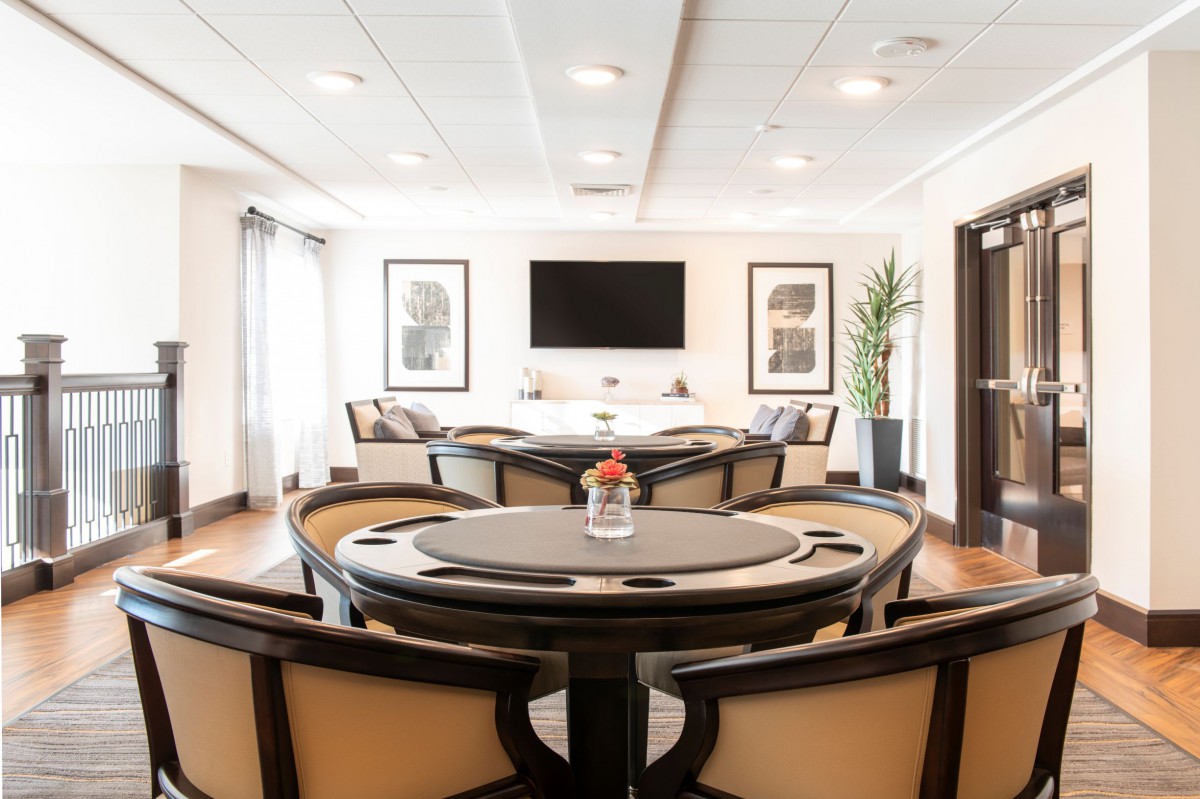 A modern game room featuring a poker table, ample seating, and a large television on the wall.