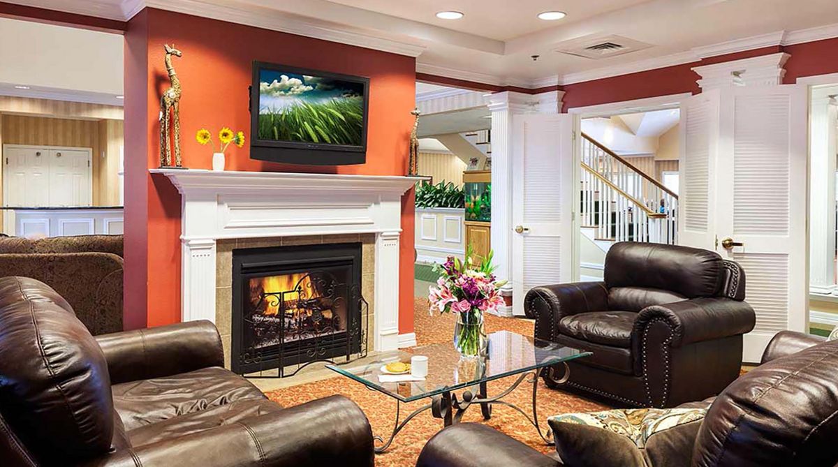 A cozy living room featuring a fireplace, leather seating, and a TV mounted above the mantel.