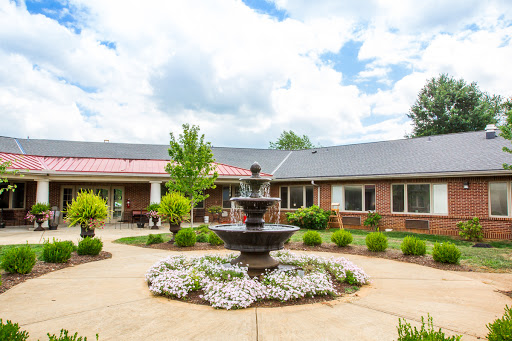 A serene courtyard featuring a central fountain surrounded by lush greenery and colorful flowers.