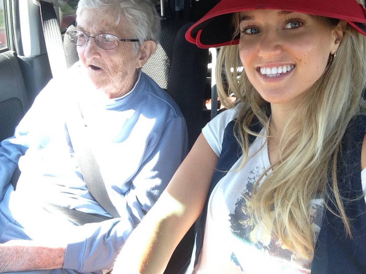 A cheerful selfie in a car with an elderly passenger and a woman wearing a red hat.