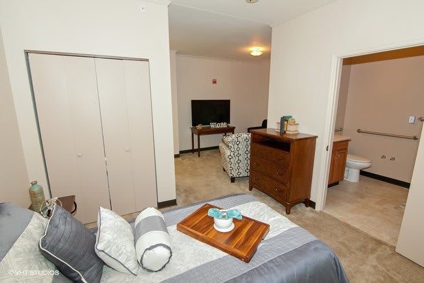 A cozy bedroom with a view into a living area featuring a television and comfortable seating.