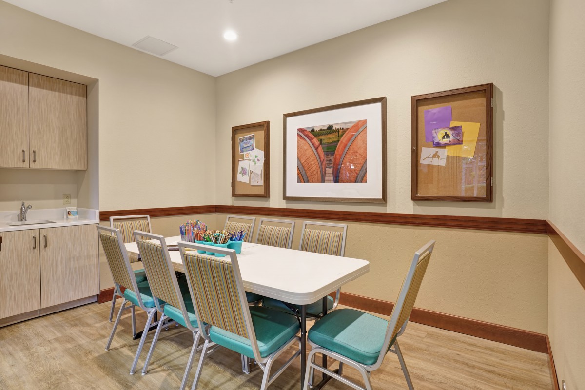 A small conference room with a white table and blue chairs, adorned with framed artwork on the walls.