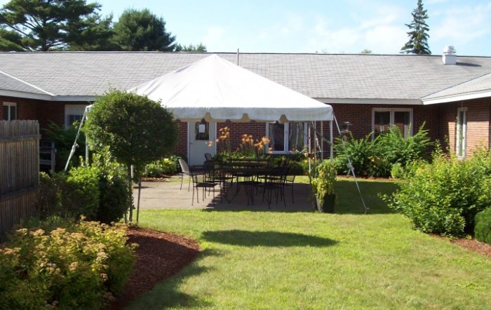 A beautifully landscaped garden with a seating area under a white tent.
