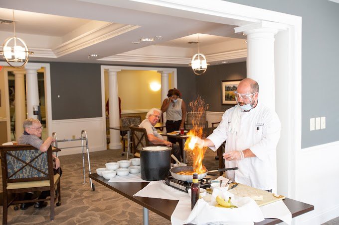 A chef performs a cooking demonstration with flames in a dining area.
