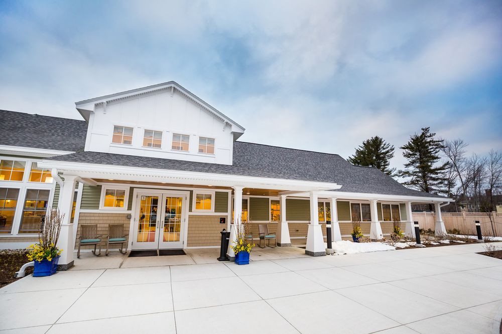 A modern residential building with a spacious porch and a cloudy sky backdrop.