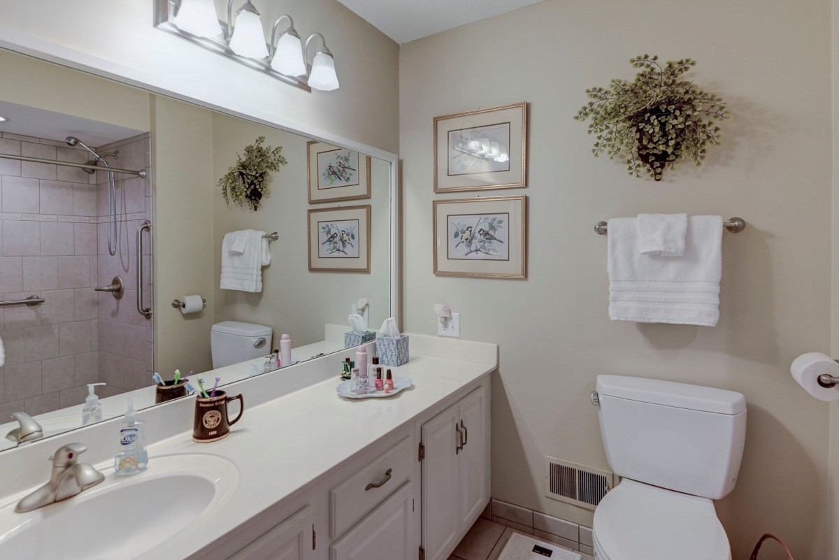 A tidy and well-decorated bathroom with a large mirror, sink, and neatly arranged decor.