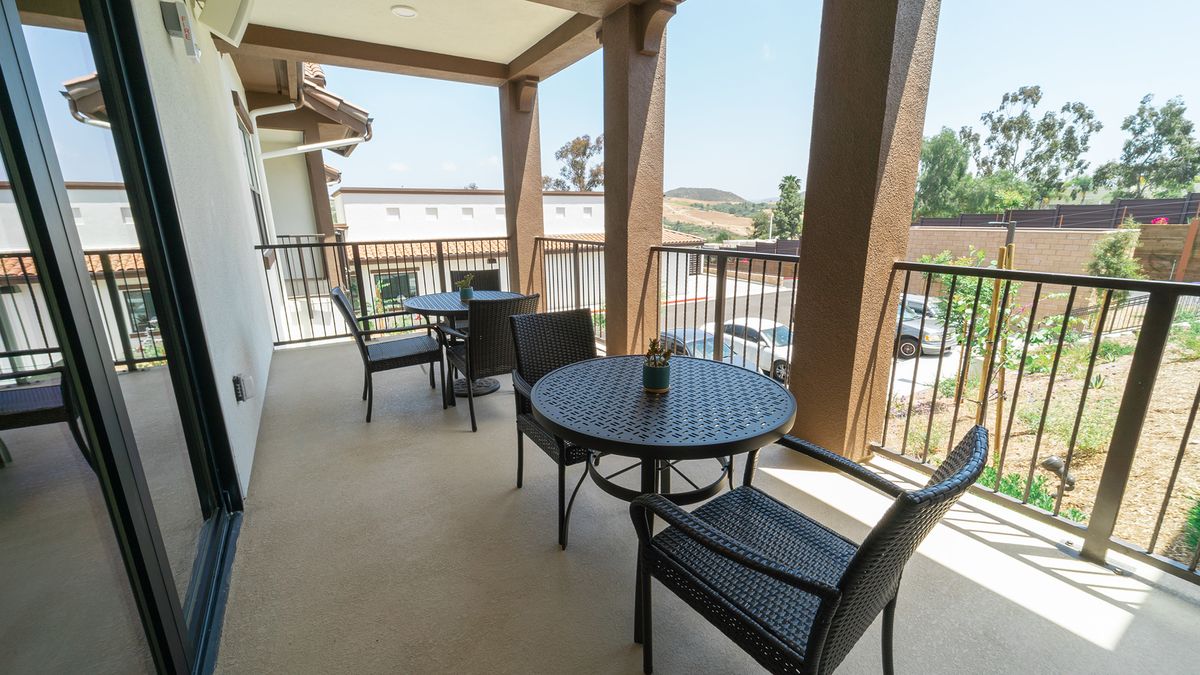 A spacious balcony with outdoor seating, featuring tables and chairs overlooking a scenic view.