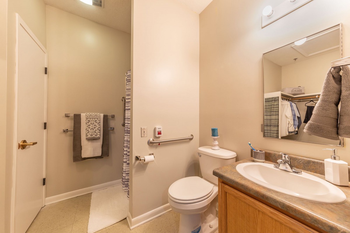 A modern and clean bathroom featuring a toilet, sink, mirror, and neatly arranged towels.