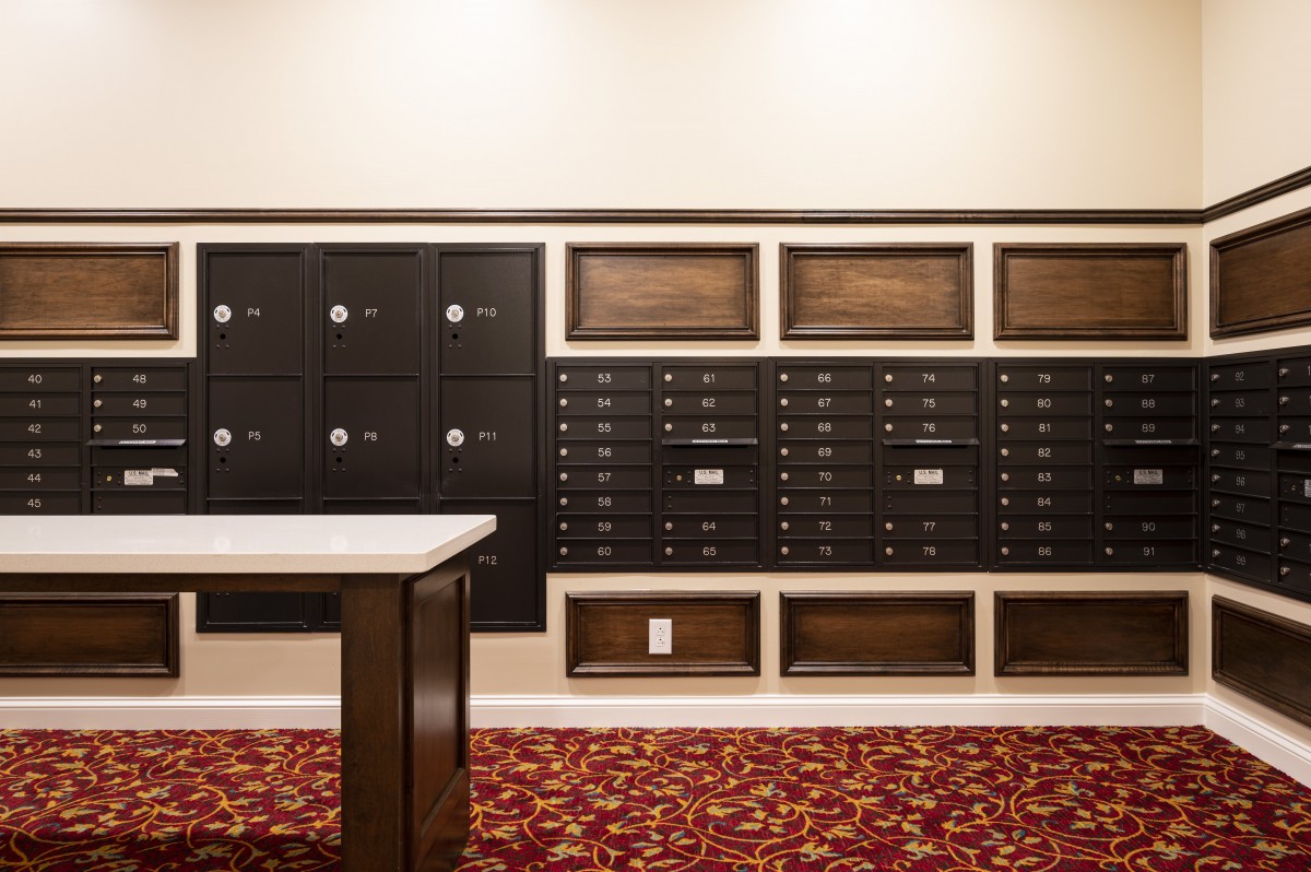 A neatly organized mailroom with black mailboxes and a red patterned carpet.