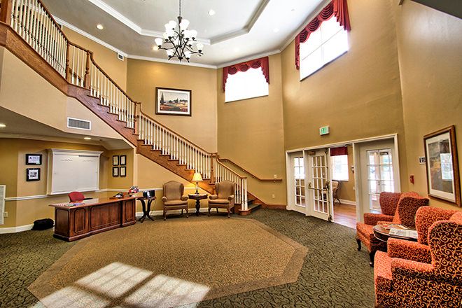 A spacious lobby with a grand staircase, elegant chandelier, and comfortable seating.