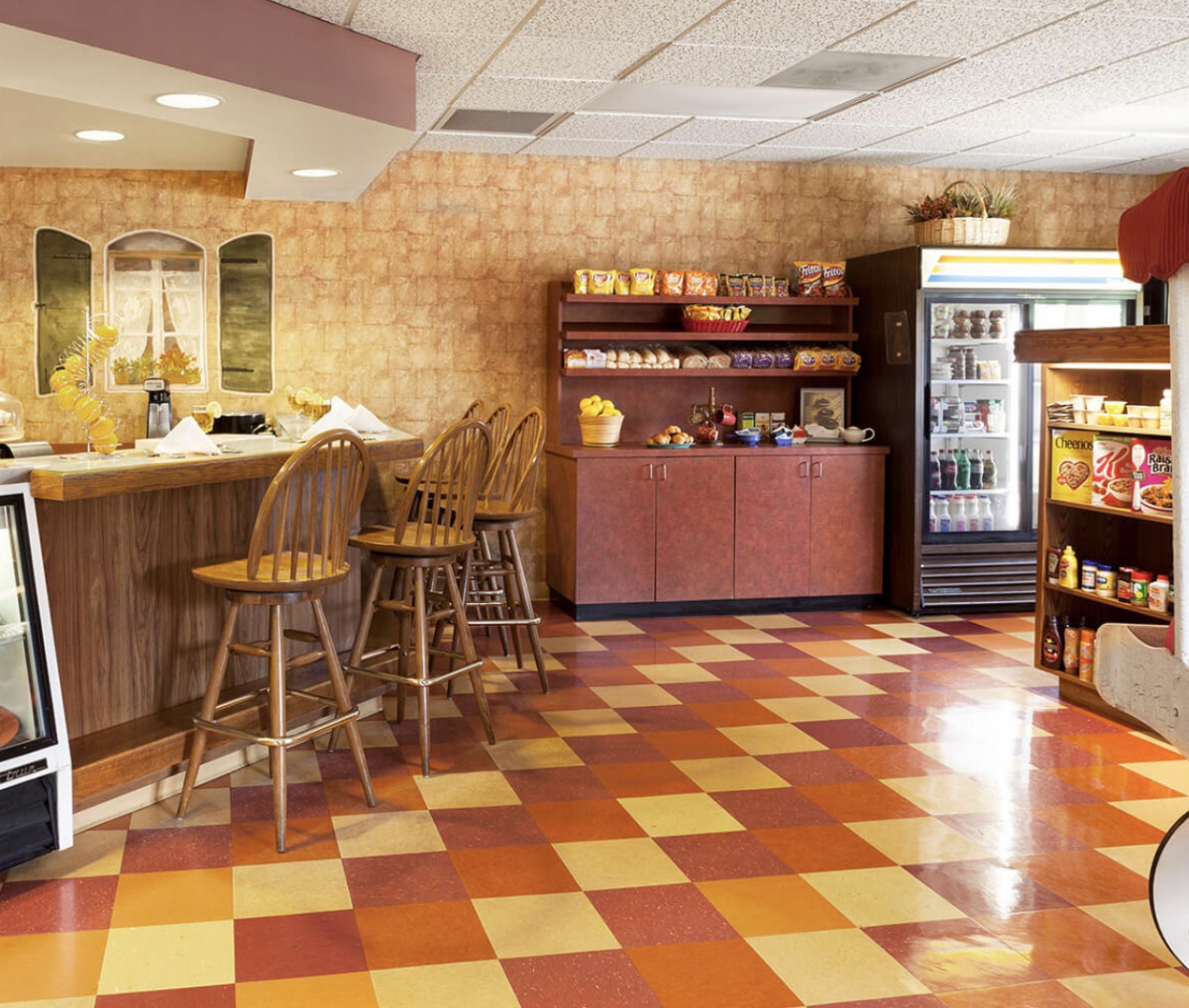 A cozy cafe interior with a counter and seating area, featuring tile flooring and a selection of snacks and beverages.