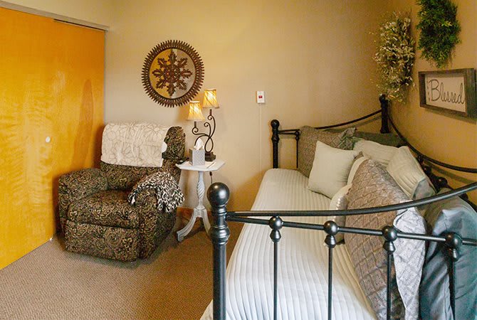 A cozy bedroom with a patterned chair, iron bed frame, and elegant decor.