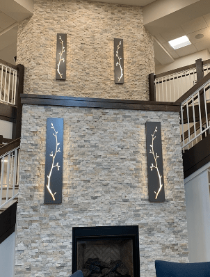 A modern interior with a stone fireplace, artwork on the wall, and dual staircases.