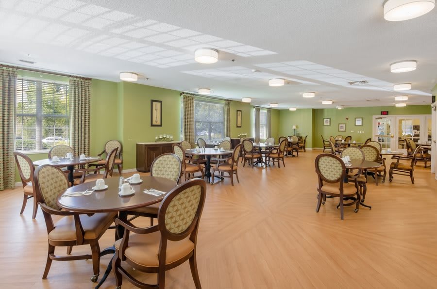 An empty dining room with neatly arranged tables and chairs, featuring large windows and a calm atmosphere.