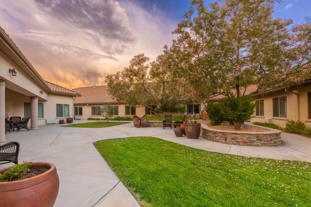 A serene courtyard at sunset with well-maintained lawns and trees surrounding a building.