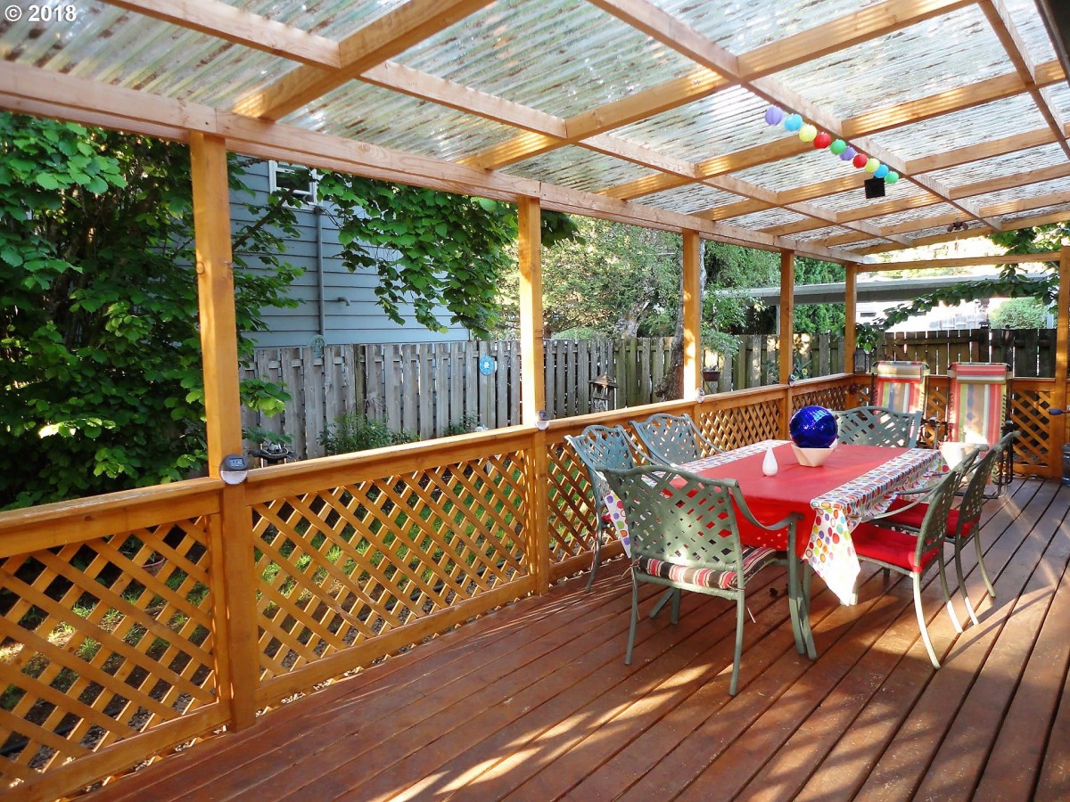 A cozy outdoor deck with a wooden pergola and dining area.