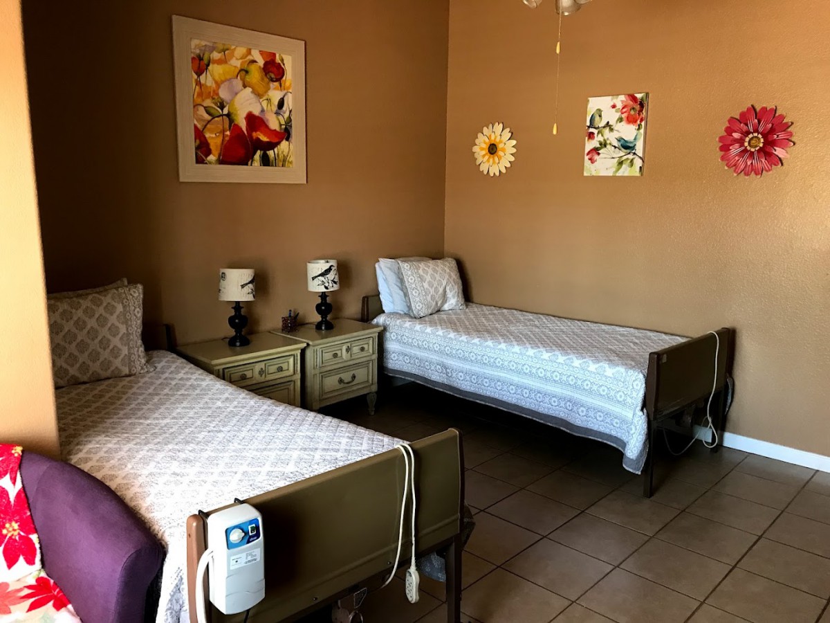 A cozy bedroom with two single beds, decorated with floral wall art and bedside lamps.