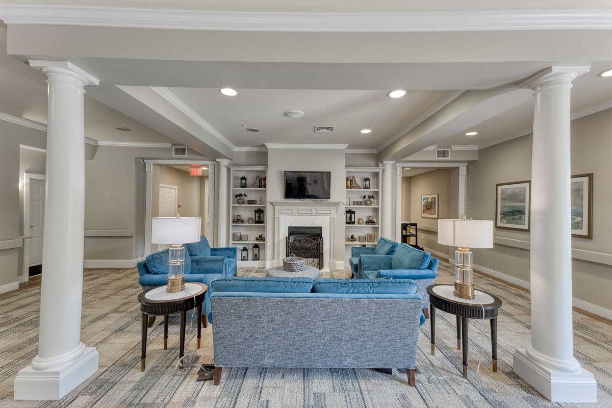 A modern living room featuring a central fireplace, blue sofas, and elegant table lamps.