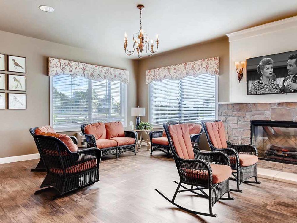 A spacious living room with ample seating, featuring rocking chairs and a cozy fireplace.