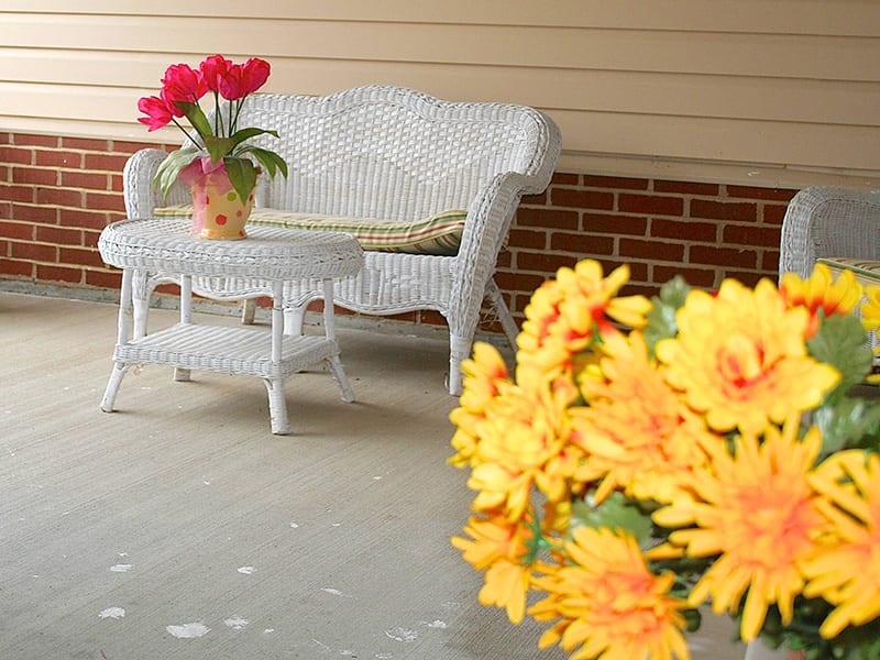 A cozy porch with wicker furniture and vibrant flowers.