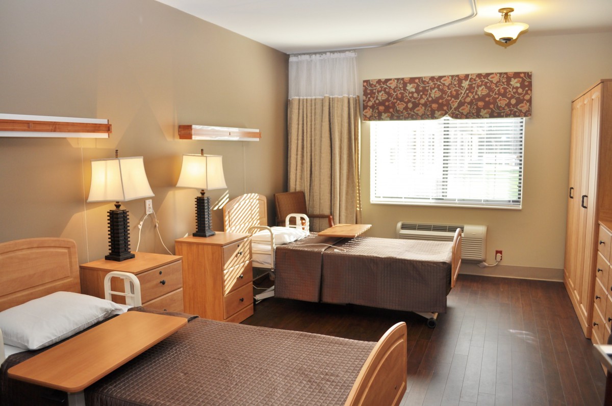 A shared hospital room with two beds and basic furnishings.