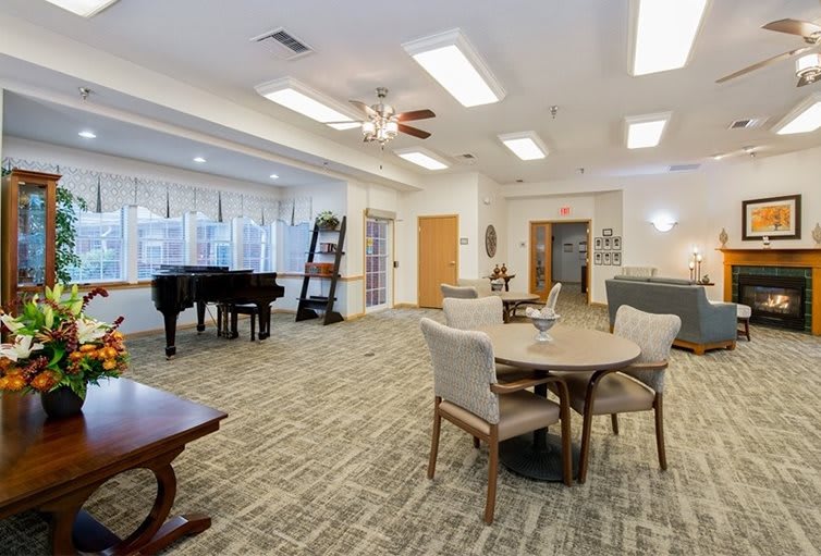 A welcoming room with a piano, tables, and chairs arranged for relaxation and socializing.